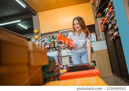 asian woman working athletic footwear store holding box 120499562