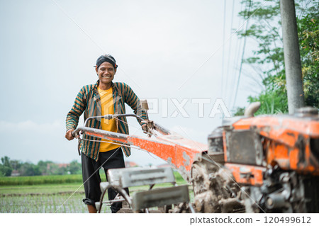 A Man Working with Agricultural Machinery in the Beautiful Lush Green Fields 120499612