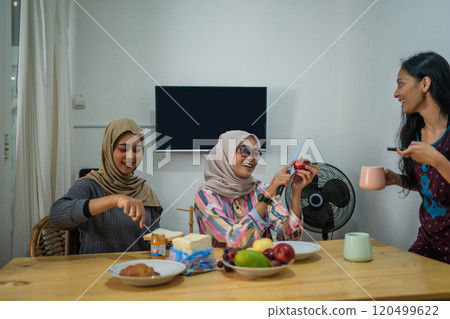Friends happily enjoying a refreshing brunch together in a cozy atmosphere 120499622