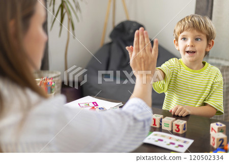 Child high-fiving woman at table Child high-fiving woman at table 120502334