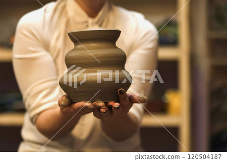 Green ceramic jug in hand close-up. Green ceramic jug in hand close-up. 120504187