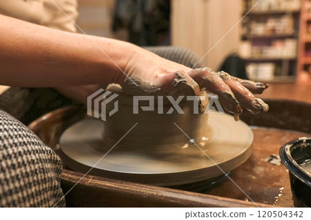 clay potter artist making pot shape on wheel pedestal 120504342