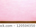 A stage with a brown wooden table against a hazy pink background 120504350