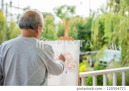 Lifestyle Asian senior old man painting picture artwork using brush and oil color on canvas, elderly people smile paint at his easel outside green nature background, Happy retirement artist activity 120504721