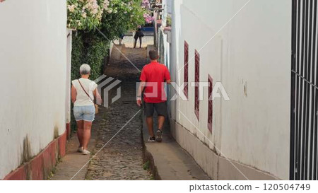 Elderly couple walking in a narrow cobblestone street in Brazil Elderly couple walking in a narrow cobblestone street in Brazil 120504749