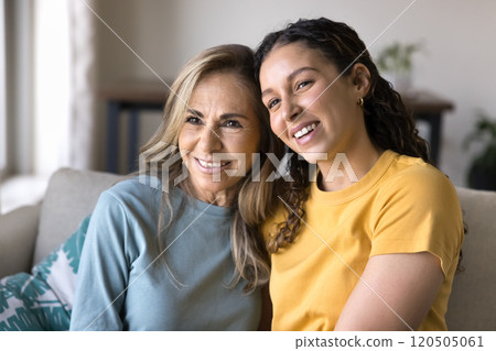 Happy Latin adult daughter woman and mature mom sitting close 120505061