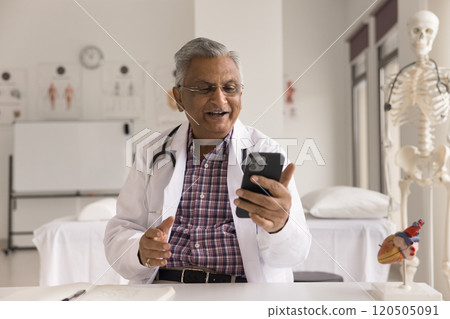 Indian physician in white coat talking to patient using smartphone Indian physician in white coat talking to patient using smartphone 120505091