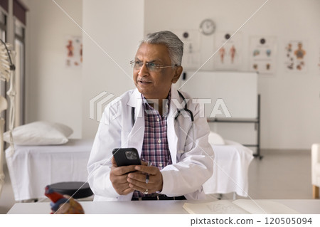 Pensive male doctor using modern smartphone in clinic office 120505094