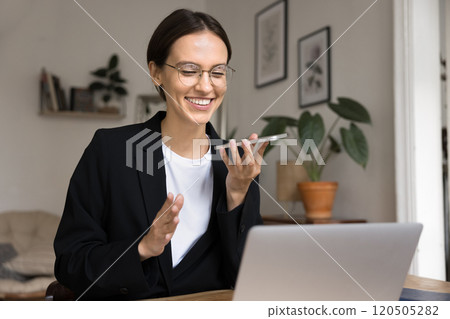 Smiling businesswoman holding smartphone leading conversation using speakerphone 120505282