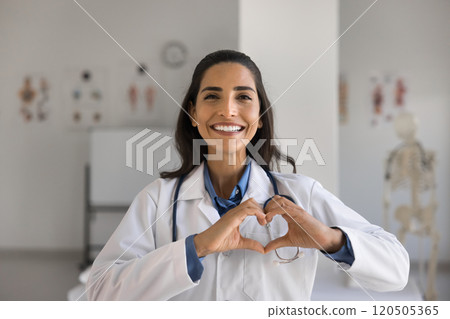 Young female cardiologist showing love symbol with joined fingers 120505365