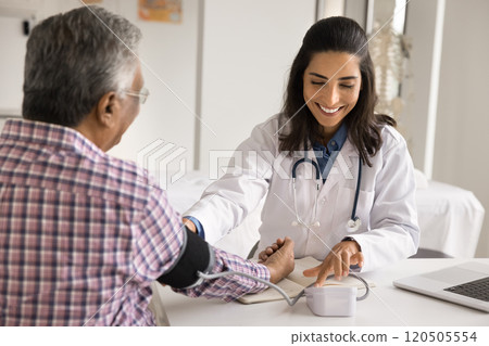 Female doctor examining arterial blood pressure of elderly male patient 120505554