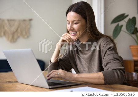 Smiling woman using laptop seated at workplace home office 120505580