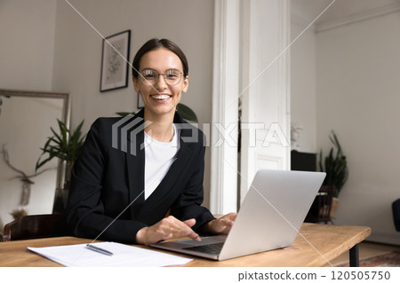 Happy female office employee posing seated at workplace Happy female office employee posing seated at workplace 120505750