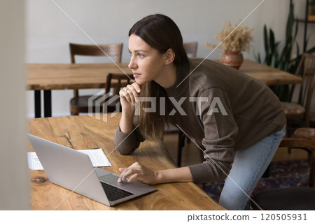Woman working on laptop, looks away, analyzing data, making decisions Woman working on laptop, looks away, analyzing data, making decisions 120505931