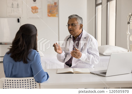 Indian male doctor asks patient about symptoms during visit Indian male doctor asks patient about symptoms during visit 120505970