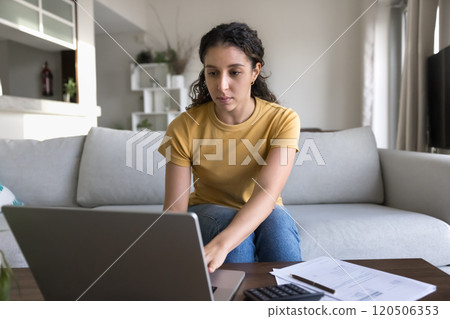 Serious young Latin accountant girl doing financial paperwork at home Serious young Latin accountant girl doing financial paperwork at home 120506353