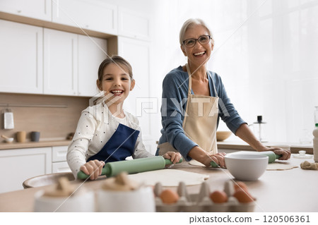 Granny her granddaughter wear aprons cooking, posing for camera 120506361