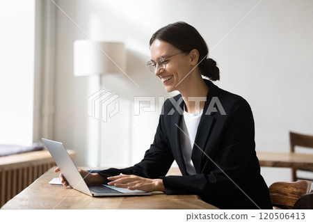 Businesswoman working seated at table with laptop 120506413
