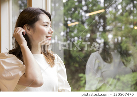 一位年輕女子在雨後從室內向外望去 120507470