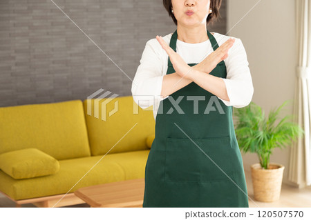 A middle-aged housewife wearing an apron making a cross sign with her hand A middle-aged housewife wearing an apron making a cross sign with her hand 120507570
