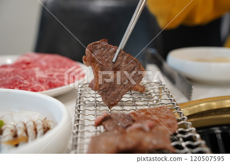 Beef sirloin being grilled on charcoal grill with chopsticks Beef sirloin being grilled on charcoal grill with chopsticks 120507595