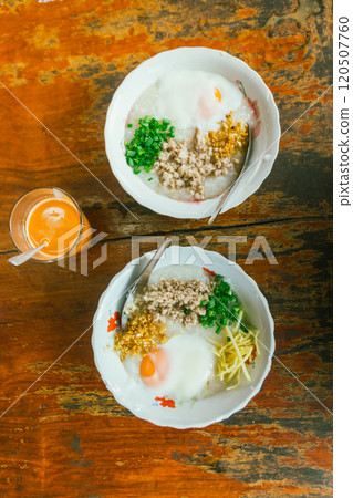 Hot Chinese congee (rice porridge) with minced pork on wooden table Hot Chinese congee (rice porridge) with minced pork on wooden table 120507760