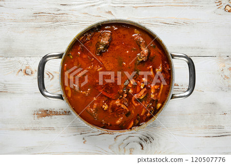 Overhead view of a pot of rich beef stew on a white wooden table Overhead view of a pot of rich beef stew on a white wooden table 120507776