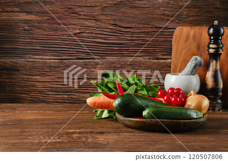 Fresh vegetables arranged on a wooden table with rustic backdrop in a cozy kitchen setting 120507806