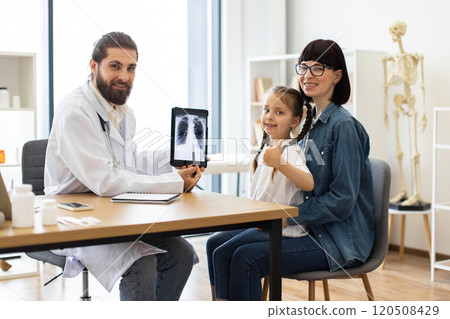 Doctor shows x-ray to smiling girl and supportive mother in clinic Doctor shows x-ray to smiling girl and supportive mother in clinic 120508429