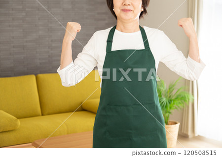 一位穿著圍裙的中年婦女家庭主婦在自家客廳打拳 一位穿著圍裙的中年婦女家庭主婦在自家客廳打拳 120508515