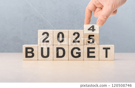 2025 Budget planning concept. Hand flips wooden cube and changes inscription BUDGET 2024 to BUDGET 2024 with grey background, copy space. Budgeting concept 2025 Budget planning concept. Hand flips wooden cube and changes inscription BUDGET 2024 to BUDGET 2024 with grey background, copy space. Budgeting concept 120508746