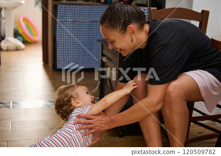 Joyful interaction between mother and child on wooden floor 120509782