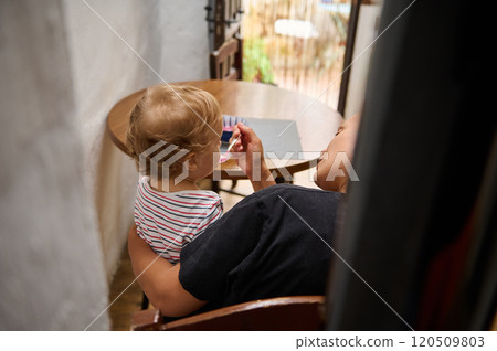 Mother feeding her baby at a cozy wooden table setting Mother feeding her baby at a cozy wooden table setting 120509803