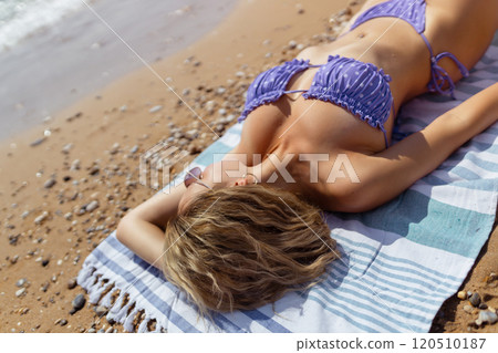 Beautiful woman with beach towel on sand near sea 120510187