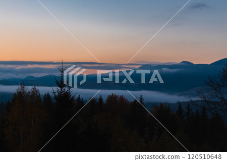 Amazing Carpathian mountains in morning haze. Foggy mountain hills against sunrise sky. Picturesque mountains landscape with copy space. Scenic highland in twilight. Tranquil nature in dawn dusk. 120510648