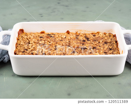Oatmeal porridge granola cake in white baking tray on green 120511389