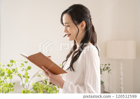A young woman looking at her system notebook in the living room A young woman looking at her system notebook in the living room 120512599