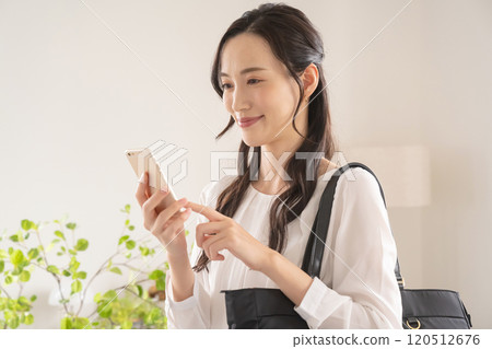 A businesswoman operating a smartphone indoors 120512676