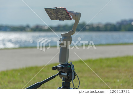 smartphone is mounted on a studicam and mounted on a tripod, a blurry background with bokeh elements 120513721