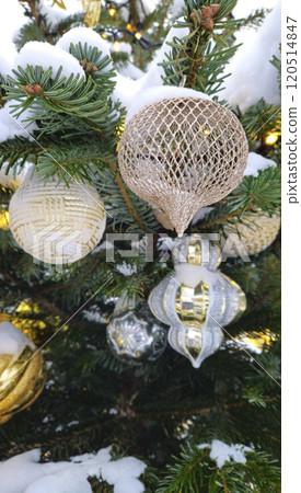 Branches of Christmas tree with beautiful decorations covered with snow Branches of Christmas tree with beautiful decorations covered with snow 120514847