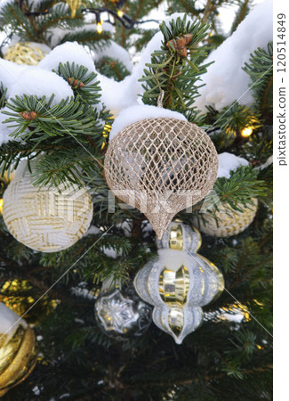 Branches of Christmas tree with beautiful decorations covered with snow Branches of Christmas tree with beautiful decorations covered with snow 120514849