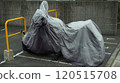 Motorcycle covered with tarpaulin parked in street parking lot 120515708