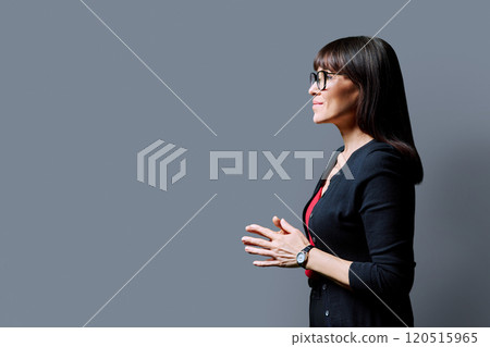 Profile view of smiling middle aged woman, gray background, copy space 120515965