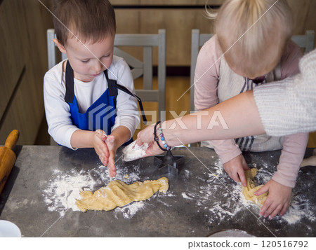 Mother and kids make cookies together in a lively kitchen, sprinkling flour as they shape dough on a cluttered countertop. Little hands eagerly form cookies, creating a fun family baking scene. Mother and kids make cookies together in a lively kitchen, sprinkling flour as they shape dough on a cluttered countertop. Little hands eagerly form cookies, creating a fun family baking scene. 120516792