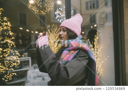 A woman is photographing a Christmas tree in a store window A woman is photographing a Christmas tree in a store window 120516869
