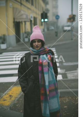 A woman in a pink hat and scarf stands on a crosswalk 120517029