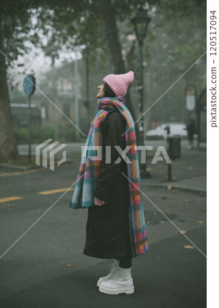 A woman in a pink hat and colorful scarf stands on the street A woman in a pink hat and colorful scarf stands on the street 120517094