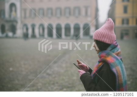 A woman in a pink hat and scarf is looking at her cell phone 120517101