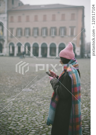 A woman in a pink hat and scarf stands in front of a building 120517104