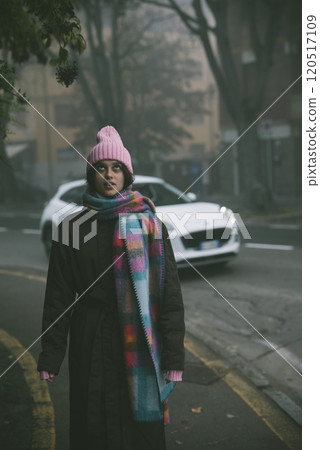 A woman in a pink hat and scarf stands on the roadside A woman in a pink hat and scarf stands on the roadside 120517109